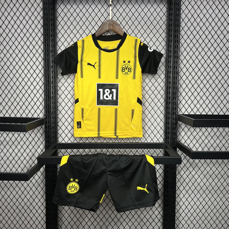 Criança vestindo o Kit Infantil Borussia Dortmund Home 2024/25 da PUMA, com camisa amarela e detalhes pretos, escudo do clube no peito e logotipo da PUMA, ideal para pequenos torcedores do time alemão.