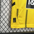 Criança vestindo o Kit Infantil Borussia Dortmund Home 2024/25 da PUMA, com camisa amarela e detalhes pretos, escudo do clube no peito e logotipo da PUMA, ideal para pequenos torcedores do time alemão.
