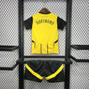 Criança vestindo o Kit Infantil Borussia Dortmund Home 2024/25 da PUMA, com camisa amarela e detalhes pretos, escudo do clube no peito e logotipo da PUMA, ideal para pequenos torcedores do time alemão.