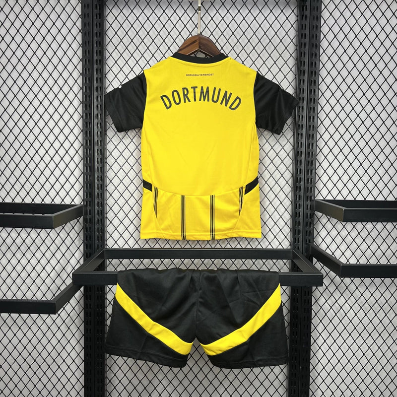 Criança vestindo o Kit Infantil Borussia Dortmund Home 2024/25 da PUMA, com camisa amarela e detalhes pretos, escudo do clube no peito e logotipo da PUMA, ideal para pequenos torcedores do time alemão.