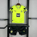 Criança usando o Kit Infantil Borussia Dortmund “Especial Anos 90” 2024/25 da PUMA, com camisa amarela em estilo retrô, gráficos ousados em preto e detalhes clássicos que remetem à década de 1990.