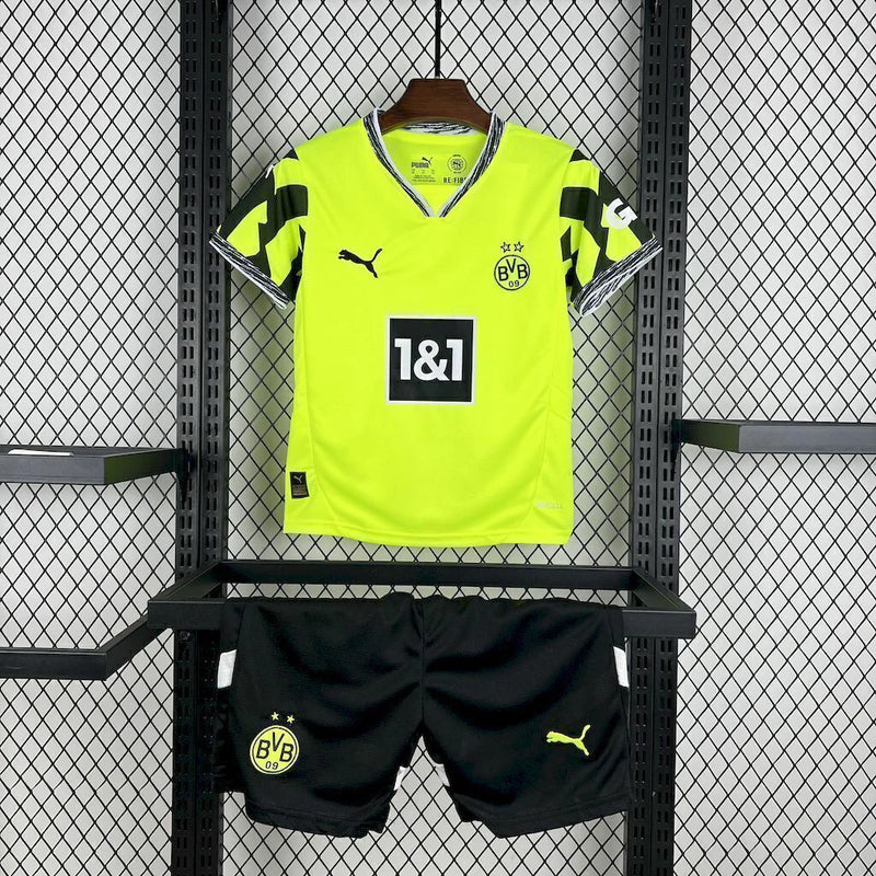 Criança usando o Kit Infantil Borussia Dortmund “Especial Anos 90” 2024/25 da PUMA, com camisa amarela em estilo retrô, gráficos ousados em preto e detalhes clássicos que remetem à década de 1990.