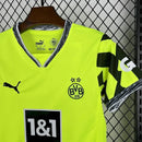 Criança usando o Kit Infantil Borussia Dortmund “Especial Anos 90” 2024/25 da PUMA, com camisa amarela em estilo retrô, gráficos ousados em preto e detalhes clássicos que remetem à década de 1990.