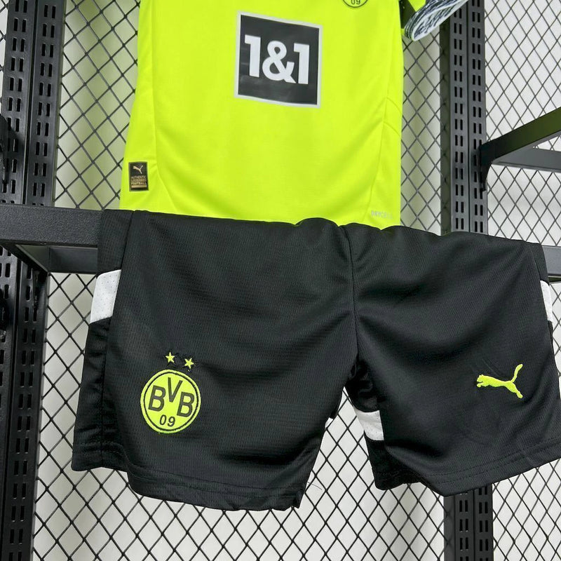 Criança usando o Kit Infantil Borussia Dortmund “Especial Anos 90” 2024/25 da PUMA, com camisa amarela em estilo retrô, gráficos ousados em preto e detalhes clássicos que remetem à década de 1990.