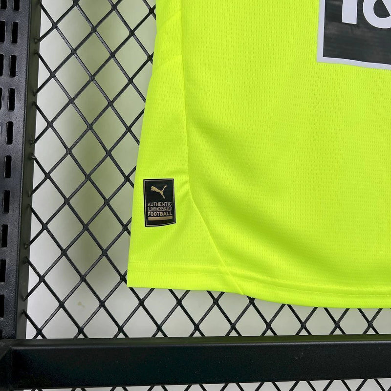 Criança usando o Kit Infantil Borussia Dortmund “Especial Anos 90” 2024/25 da PUMA, com camisa amarela em estilo retrô, gráficos ousados em preto e detalhes clássicos que remetem à década de 1990.