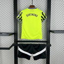 Criança usando o Kit Infantil Borussia Dortmund “Especial Anos 90” 2024/25 da PUMA, com camisa amarela em estilo retrô, gráficos ousados em preto e detalhes clássicos que remetem à década de 1990.