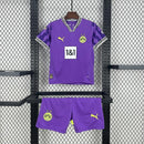 Criança com o Kit Infantil Goleiro Borussia Dortmund “Especial Anos 90” 2024/25 da PUMA, vestindo camisa de manga longa com estampa retrô colorida, short combinando e meias, em homenagem aos goleiros clássicos dos anos 1990.