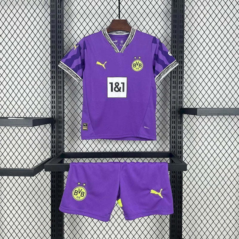 Criança com o Kit Infantil Goleiro Borussia Dortmund “Especial Anos 90” 2024/25 da PUMA, vestindo camisa de manga longa com estampa retrô colorida, short combinando e meias, em homenagem aos goleiros clássicos dos anos 1990.