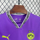Criança com o Kit Infantil Goleiro Borussia Dortmund “Especial Anos 90” 2024/25 da PUMA, vestindo camisa de manga longa com estampa retrô colorida, short combinando e meias, em homenagem aos goleiros clássicos dos anos 1990.