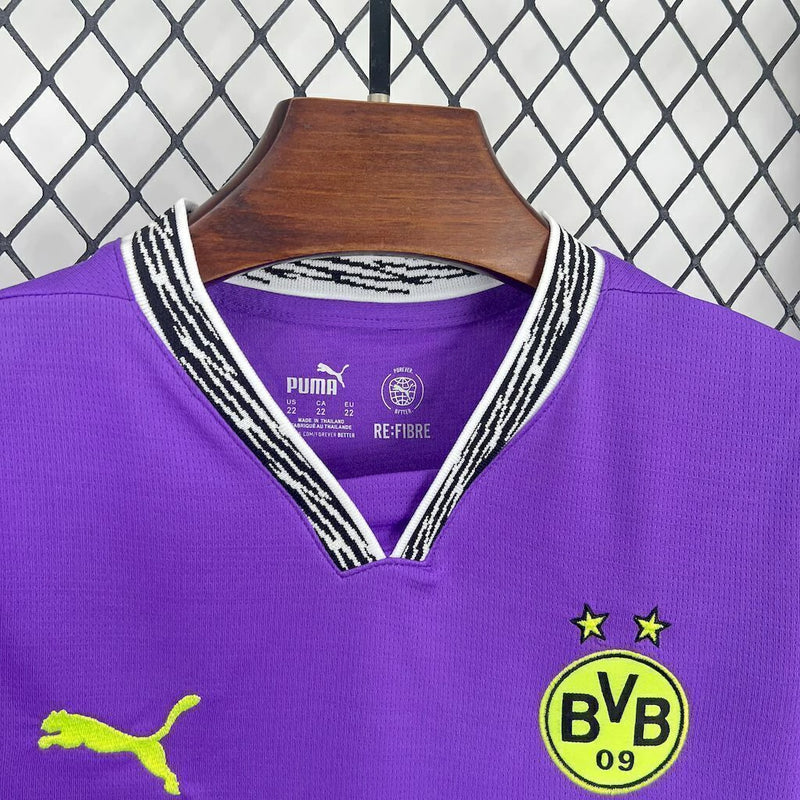 Criança com o Kit Infantil Goleiro Borussia Dortmund “Especial Anos 90” 2024/25 da PUMA, vestindo camisa de manga longa com estampa retrô colorida, short combinando e meias, em homenagem aos goleiros clássicos dos anos 1990.