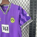 Criança com o Kit Infantil Goleiro Borussia Dortmund “Especial Anos 90” 2024/25 da PUMA, vestindo camisa de manga longa com estampa retrô colorida, short combinando e meias, em homenagem aos goleiros clássicos dos anos 1990.