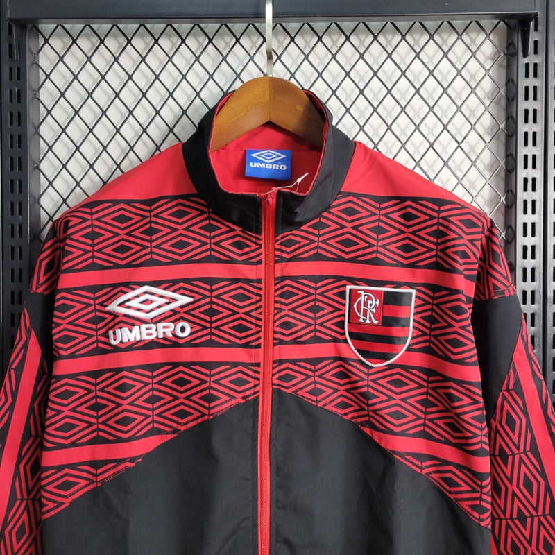 Corta Vento Flamengo Umbro Masculino nas cores vermelho e preto, com escudo do Flamengo no peito, zíper frontal e logo da Umbro – jaqueta esportiva para torcedores rubro-negros.