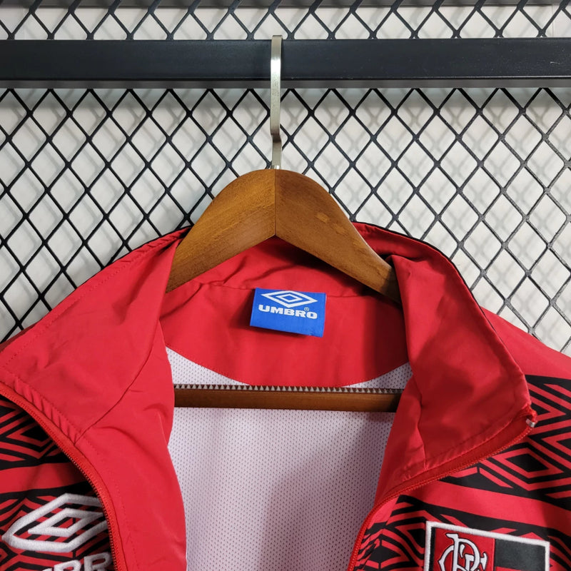 Corta Vento Flamengo Umbro Masculino nas cores vermelho e preto, com escudo do Flamengo no peito, zíper frontal e logo da Umbro – jaqueta esportiva para torcedores rubro-negros.