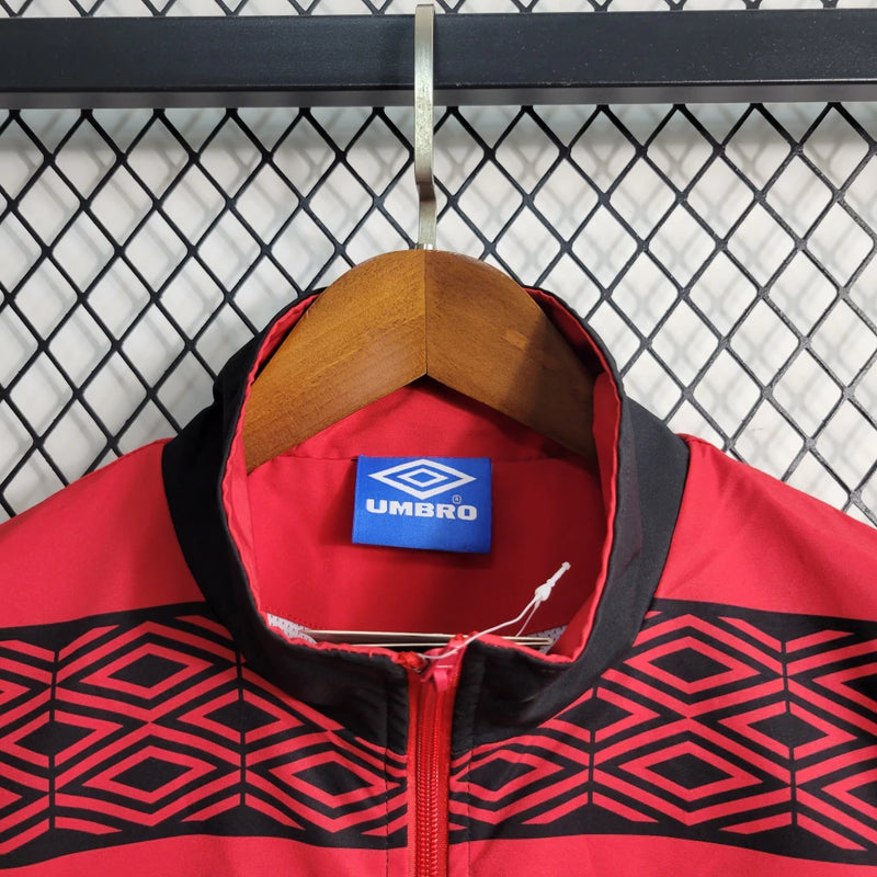 Corta Vento Flamengo Umbro Masculino nas cores vermelho e preto, com escudo do Flamengo no peito, zíper frontal e logo da Umbro – jaqueta esportiva para torcedores rubro-negros.