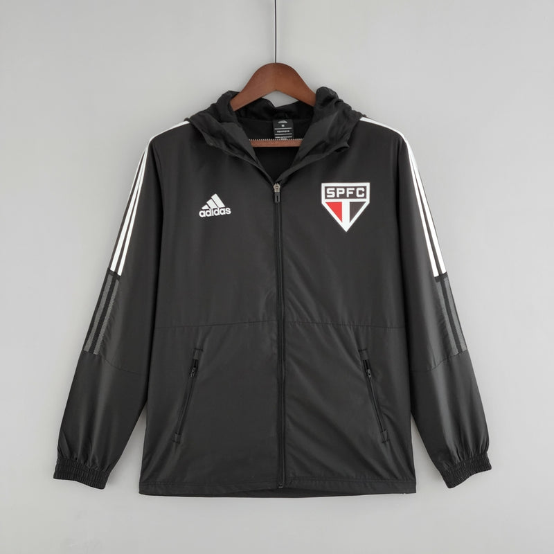 Corta Vento São Paulo 2022 Adidas Masculino na cor preta, com escudo do SPFC bordado no peito, capuz ajustável e detalhes em branco e vermelho