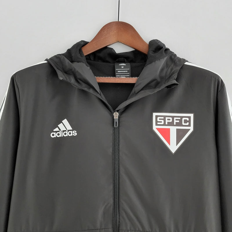 Corta Vento São Paulo 2022 Adidas Masculino na cor preta, com escudo do SPFC bordado no peito, capuz ajustável e detalhes em branco e vermelho