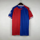 Camisa Crystal Palace Home I 2023/24 Torcedor Masculina - modelo azul com faixas verticais vermelhas, escudo do Crystal Palace bordado no peito e design tradicional da equipe londrina, confeccionada pela Macron.