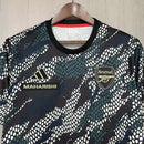 Camisa Arsenal Pré-Jogo Maharishi 2023/24 Adidas Torcedor Masculina verde com detalhes discretos, escudo do Arsenal e logo Adidas.