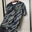 Camisa Arsenal Pré-Jogo Maharishi 2023/24 Adidas Torcedor Masculina verde com detalhes discretos, escudo do Arsenal e logo Adidas.