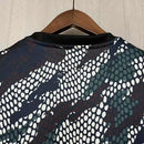 Camisa Arsenal Pré-Jogo Maharishi 2023/24 Adidas Torcedor Masculina verde com detalhes discretos, escudo do Arsenal e logo Adidas.