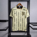 Camisa do Corinthians com estampa japonesa em katakana, escudo bordado no peito, modelo unissex em tom bege, pendurada em cabide sobre fundo de grade metálica. Design exclusivo estilo retrô edição limitada 2024.