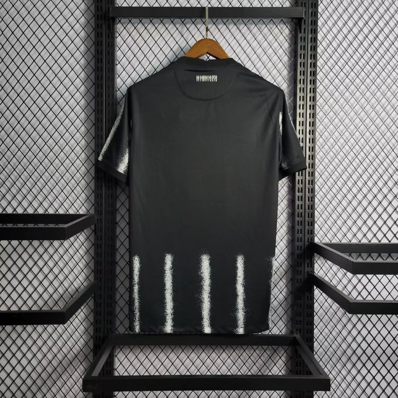 Camisa Corinthians Away 2021/22 Nike Torcedor Masculina na cor preta com listras verticais brancas, escudo bordado no peito e logo da Nike. Modelo pendurado em cabide sobre fundo metálico com grade.
