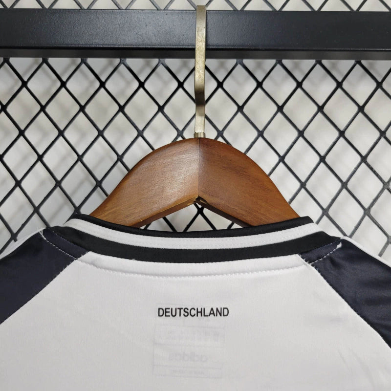 "Kit Infantil Alemanha Home 2024/25 Adidas – camisa branca com detalhes em preto e vermelho e shorts combinando, uniforme infantil oficial da seleção alemã, leve, respirável e confortável para crianças de 3 a 13 anos."
