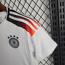 "Kit Infantil Alemanha Home 2024/25 Adidas – camisa branca com detalhes em preto e vermelho e shorts combinando, uniforme infantil oficial da seleção alemã, leve, respirável e confortável para crianças de 3 a 13 anos."
