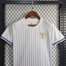 Kit Infantil Uruguai Away (2) 2024/25 – Camisa branca com detalhes em azul celeste e shorts oficial, uniforme leve, confortável e ideal para crianças de 3 a 13 anos."