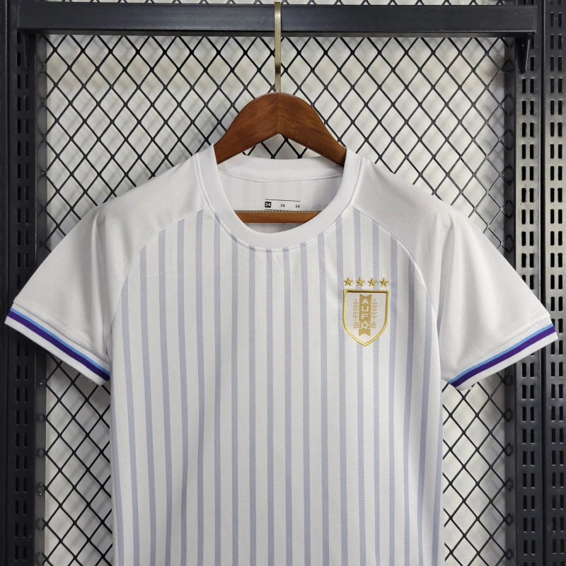 Kit Infantil Uruguai Away (2) 2024/25 – Camisa branca com detalhes em azul celeste e shorts oficial, uniforme leve, confortável e ideal para crianças de 3 a 13 anos."