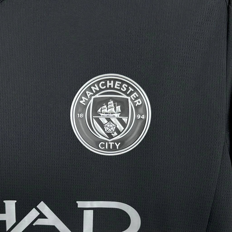 Camisa Manchester City IV 2025/26 Puma Torcedor Masculino preta com detalhes em azul, escudo do clube no peito e logo Puma bordado. Modelo da temporada, ideal para torcedores apaixonados.