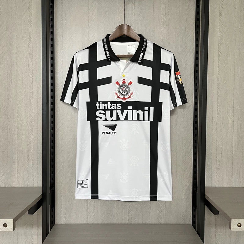 Camisa retrô Corinthians Suvinil 1990 Penalty masculina, cor branca com listras pretas horizontais e verticais, escudo bordado no peito e gola polo com detalhes da marca Penalty.