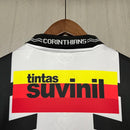 Camisa retrô Corinthians Suvinil 1990 Penalty masculina, cor branca com listras pretas horizontais e verticais, escudo bordado no peito e gola polo com detalhes da marca Penalty.