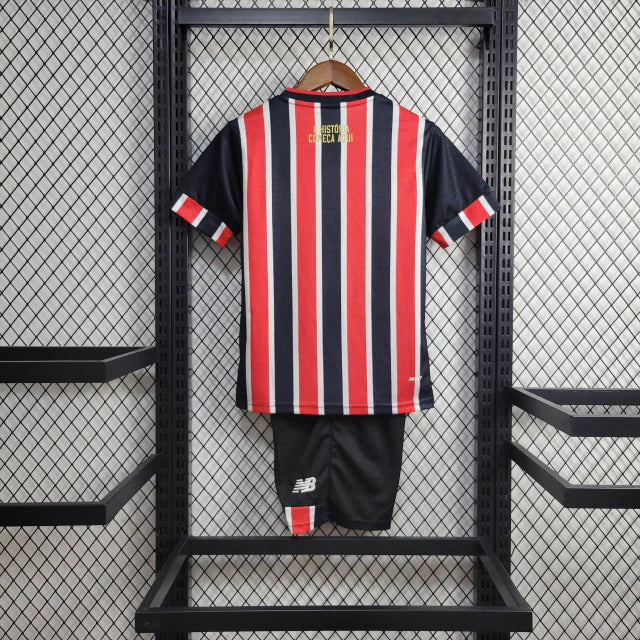 Kit Infantil São Paulo FC Away 2024/25 New Balance com camisa branca, detalhes em vermelho e preto, escudo bordado do SPFC, shorts combinando, uniforme oficial para crianças de 3 a 13 anos, torcedor infantil, conforto e mobilidade, peça licenciada"