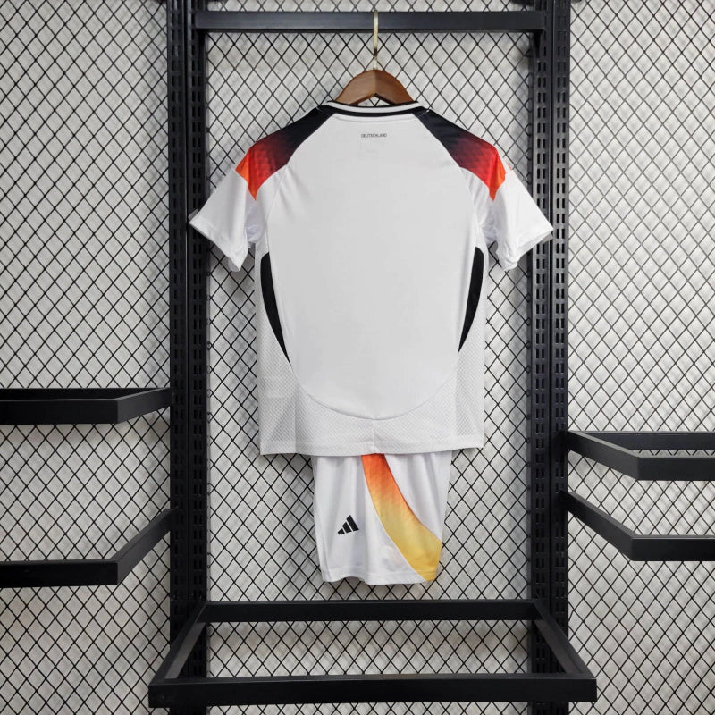 "Kit Infantil Alemanha Home 2024/25 Adidas – camisa branca com detalhes em preto e vermelho e shorts combinando, uniforme infantil oficial da seleção alemã, leve, respirável e confortável para crianças de 3 a 13 anos."
