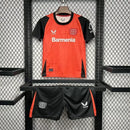 Kit Infantil Bayer Leverkusen Home 2024/25 Castore – uniforme oficial vermelho com detalhes pretos, composto por camisa e short, disponível do tamanho 3-4 anos ao 12-13 anos."
