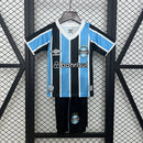 "Kit Infantil Grêmio Home 2024/25 Umbro, camisa azul, preta e branca listrada com shorts e meias combinando, uniforme oficial para crianças de 3 a 13 anos torcedoras do Grêmio."