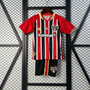 Kit Infantil São Paulo Away 2025/26 Adidas com camisa branca, detalhes em vermelho e preto, escudo do São Paulo bordado no peito, short oficial incluso, ideal para torcedores mirins, produto oficial licenciado.”