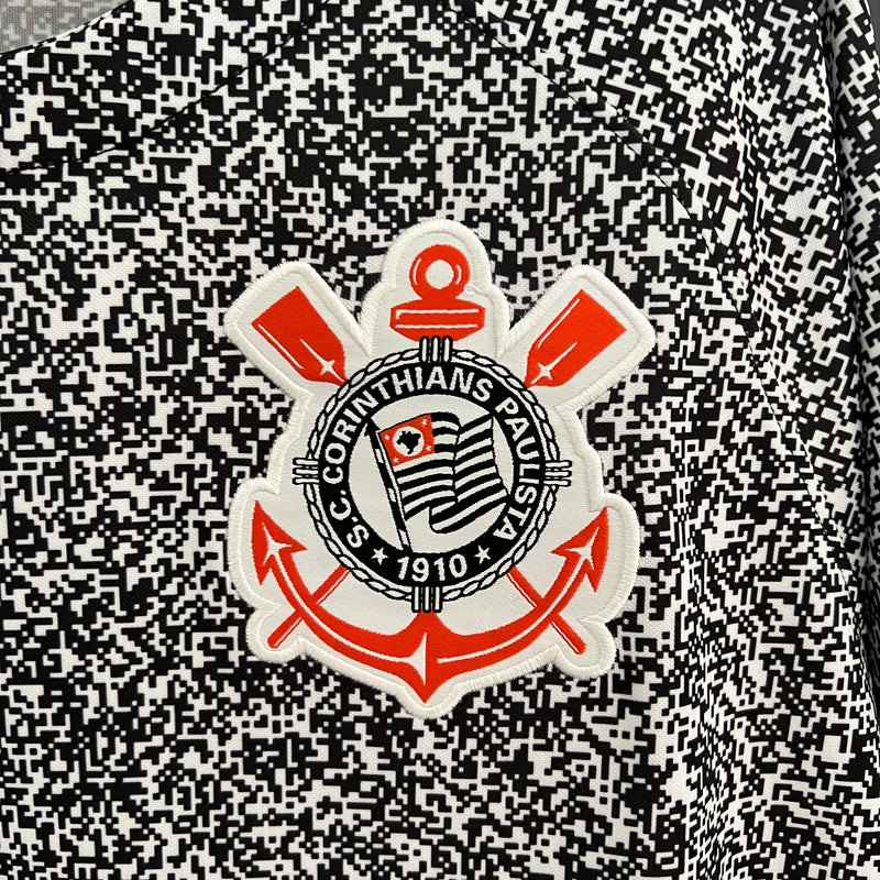 Camisa Corinthians 2023/24 Edição Especial Nike Torcedor Masculina com estampa preta e branca estilo caderno universitário, escudo bordado e logo Nike vermelho, pendurada em cabide contra uma grade metálica.