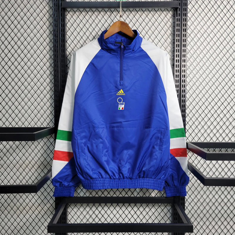 Corta-Vento Itália Edição ICON 2023/24 Adidas Masculino, azul vibrante, com escudo da seleção italiana e logo Adidas em destaque, zíper frontal completo e bolsos funcionais, ideal para torcedores e uso casual.”