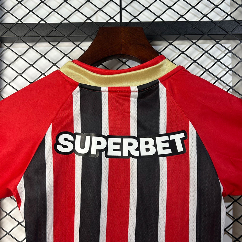 Kit Infantil São Paulo Away 2025/26 Adidas com camisa branca, detalhes em vermelho e preto, escudo do São Paulo bordado no peito, short oficial incluso, ideal para torcedores mirins, produto oficial licenciado.”