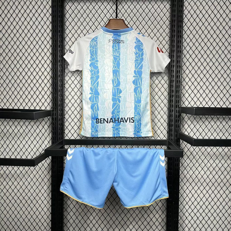 Kit Infantil Málaga CF Home I 2024/25 Hummel com camisa e short, uniforme infantil azul, tecido leve e respirável, ideal para jogos, treinos e jovens torcedores do Málaga CF."