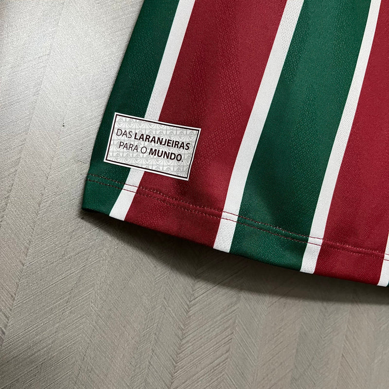 
Camisa Fluminense Home 2025/26 Umbro Torcedor Masculina tricolor com listras verticais em verde, grená e branco, escudo bordado no peito e design moderno da temporada 2025/26
