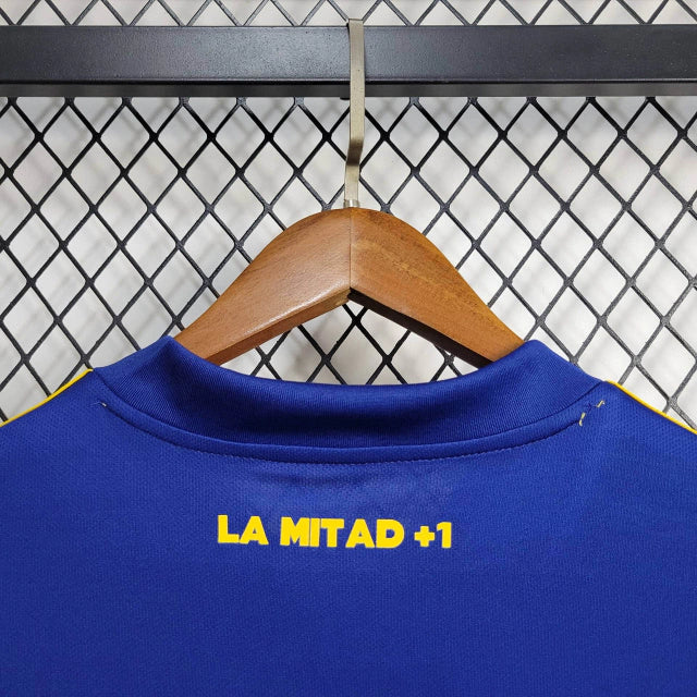 Texto alternativo para imagem:
Camisa Boca Juniors Home (1) 2020/21 Retrô Adidas Masculina azul com faixa amarela, escudo bordado e logo Adidas clássico estampado.

