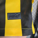 Camisa Al-Ittihad Home I 2023/24 Nike Torcedor Masculina amarela com detalhes em preto, uniforme titular do Al-Ittihad Club da Arábia Saudita, modelo torcedor com tecido leve e tecnologia Dri-FIT para absorção de suor."