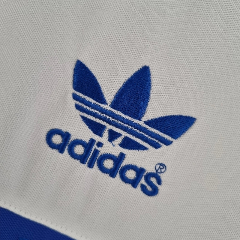 Camisa Universidad Católica Home I 1984/85 Adidas Retrô Masculina branca, modelo clássico dos anos 80 com detalhes em azul, escudo bordado e design histórico do futebol chileno.