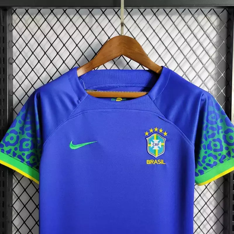 Kit Infantil Brasil Away 2022/23 Nike, camisa azul com detalhes em branco, shorts e meias combinando, uniforme oficial para crianças de 3 a 13 anos torcedoras da Seleção Brasileira."