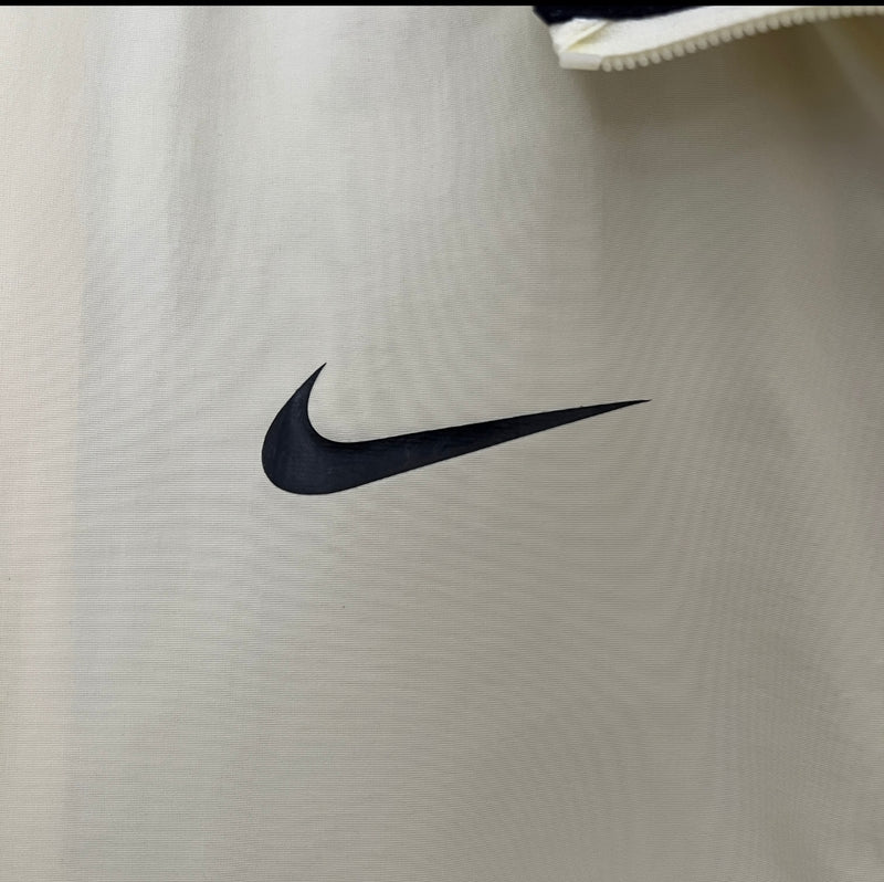 Detalhe da camisa Nike Corinthians 110 Anos 2023 bege com escudo do clube e tecido tecnológico.
