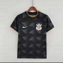 Camisa Corinthians Away II 2022/23 Nike Torcedor Masculina na cor preta com detalhes dourados, escudo bordado no peito esquerdo e logo Nike no lado direito, pendurada em cabide sobre fundo branco.