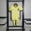 Kit Infantil Corinthians Third 2023/24 Nike, camisa amarela e preta com shorts e meias combinando, uniforme oficial para crianças de 3 a 13 anos torcedoras do Timão."